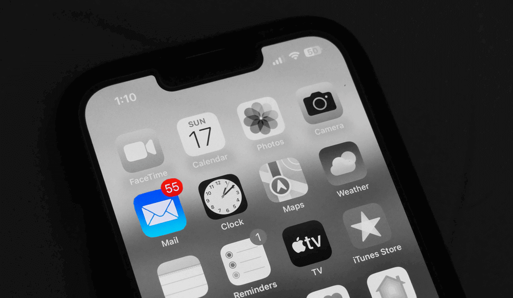 Un téléphone en noir et blanc où seule l'appli de messagerie est en couleur et indique 55 messages non lus